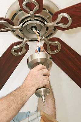 Ceil fan being hung up by a man.