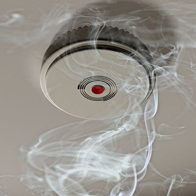 Smoke alarm with smoke around it.
